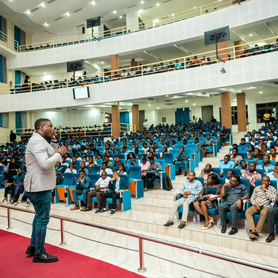 Kenny speaking to an audience in a large auditorium