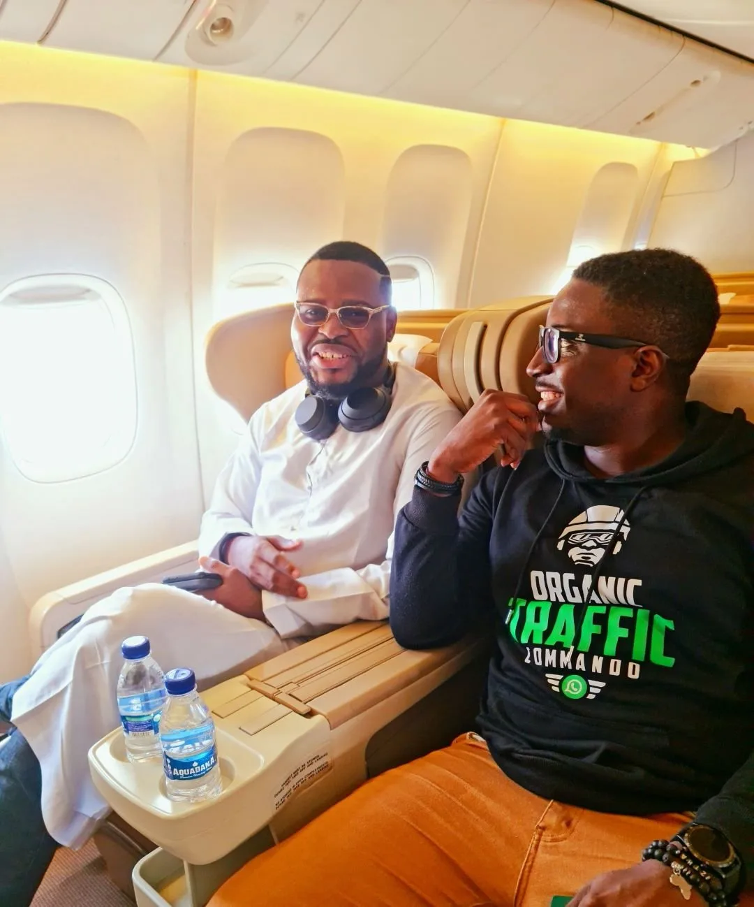 Kenny seated with a companion aboard an aircraft
