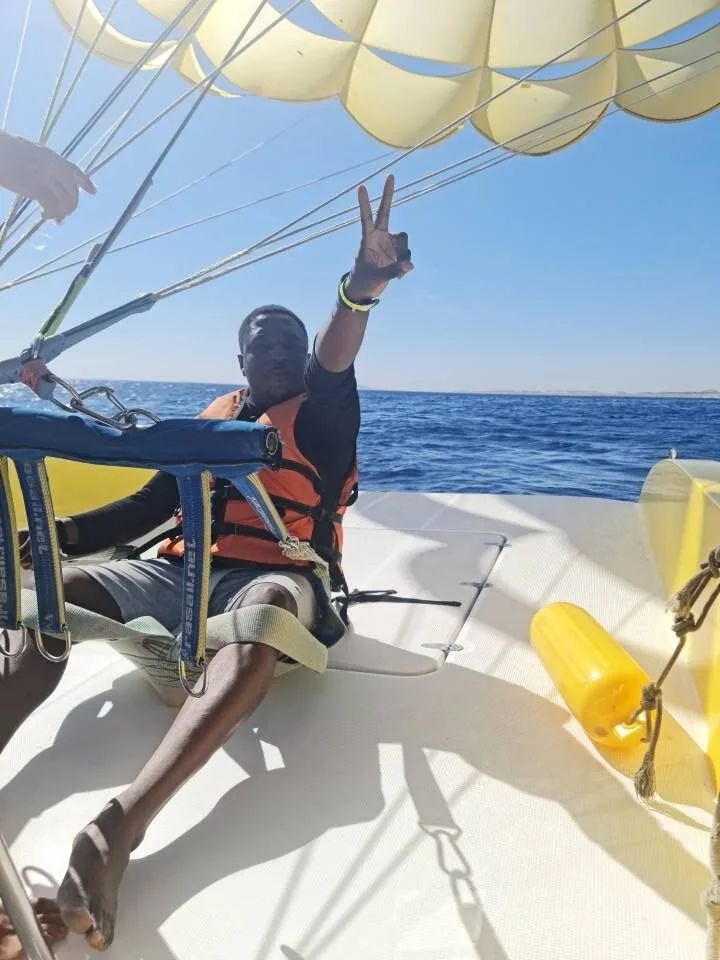 Kenny on a boat beneath a parasailing canopy